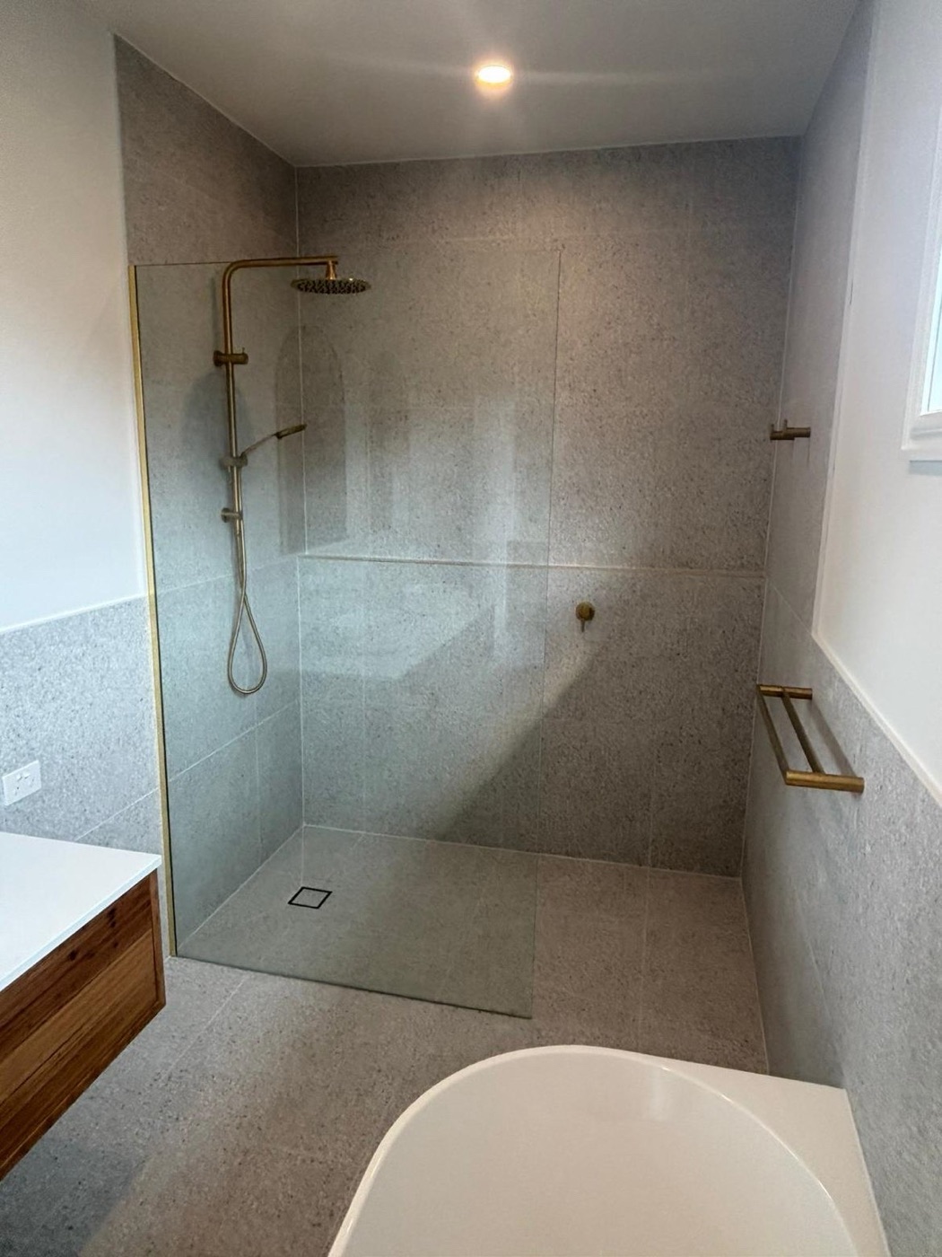 Bathroom walk-in shower with brass rail shower, glass screen and freestanding bath