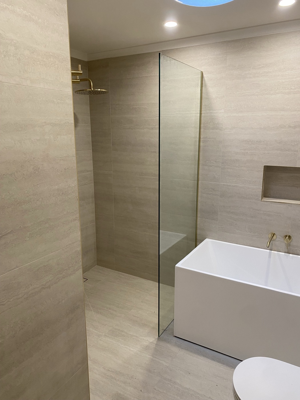 Renovated ensuite with brass tapware and stone tiling