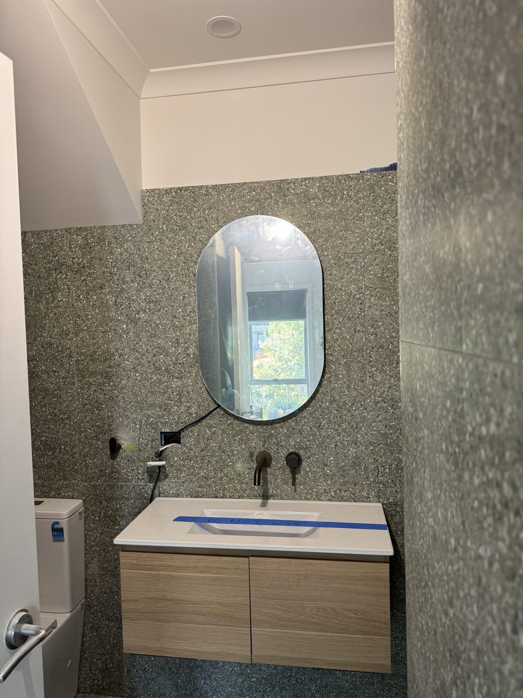 Powder room with terrazzo tiling, oval mirror and timber vanity