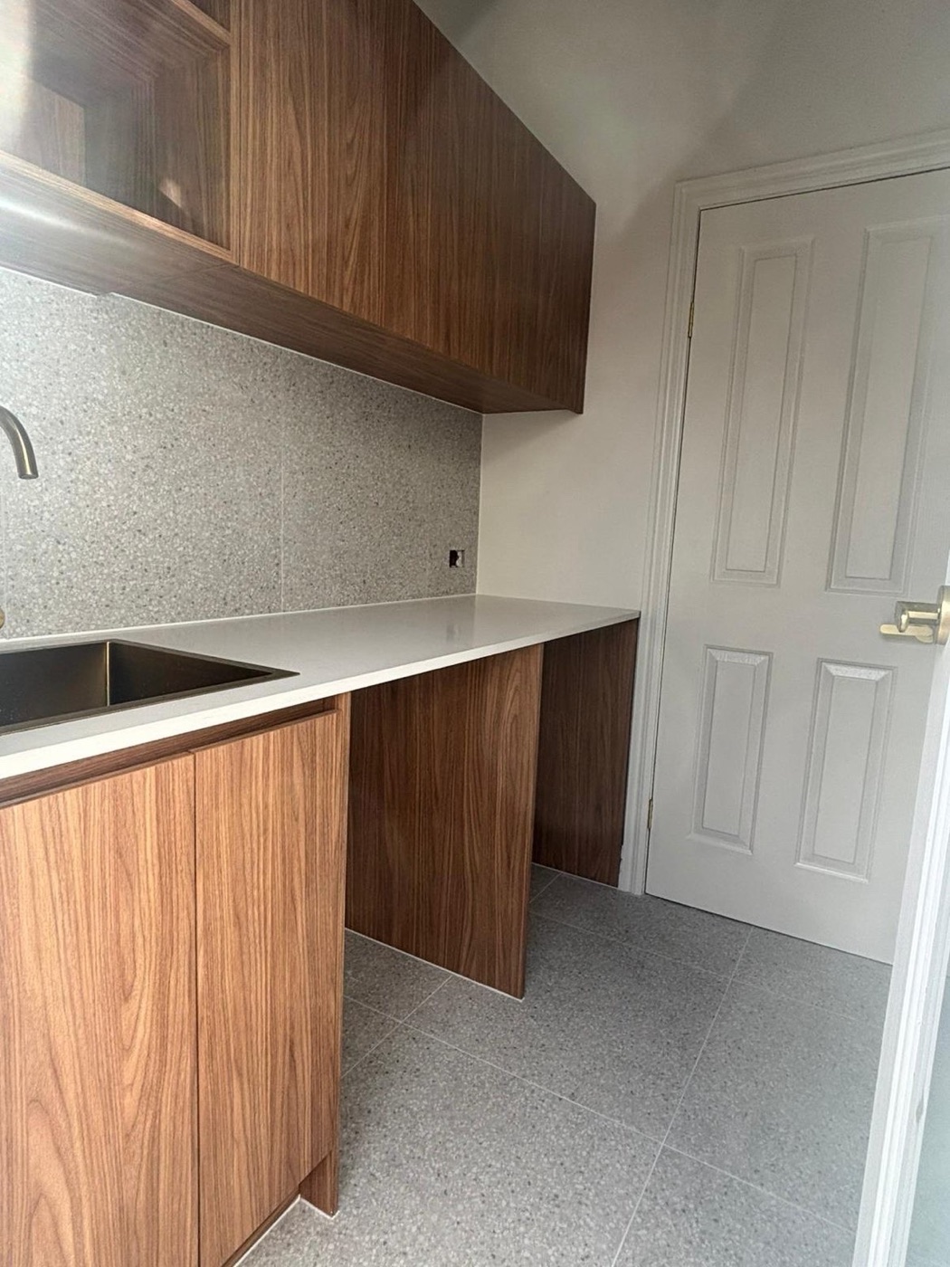 Laundry with walnut timber joinery, terrazzo splashback, stone benchtop and undermount sink